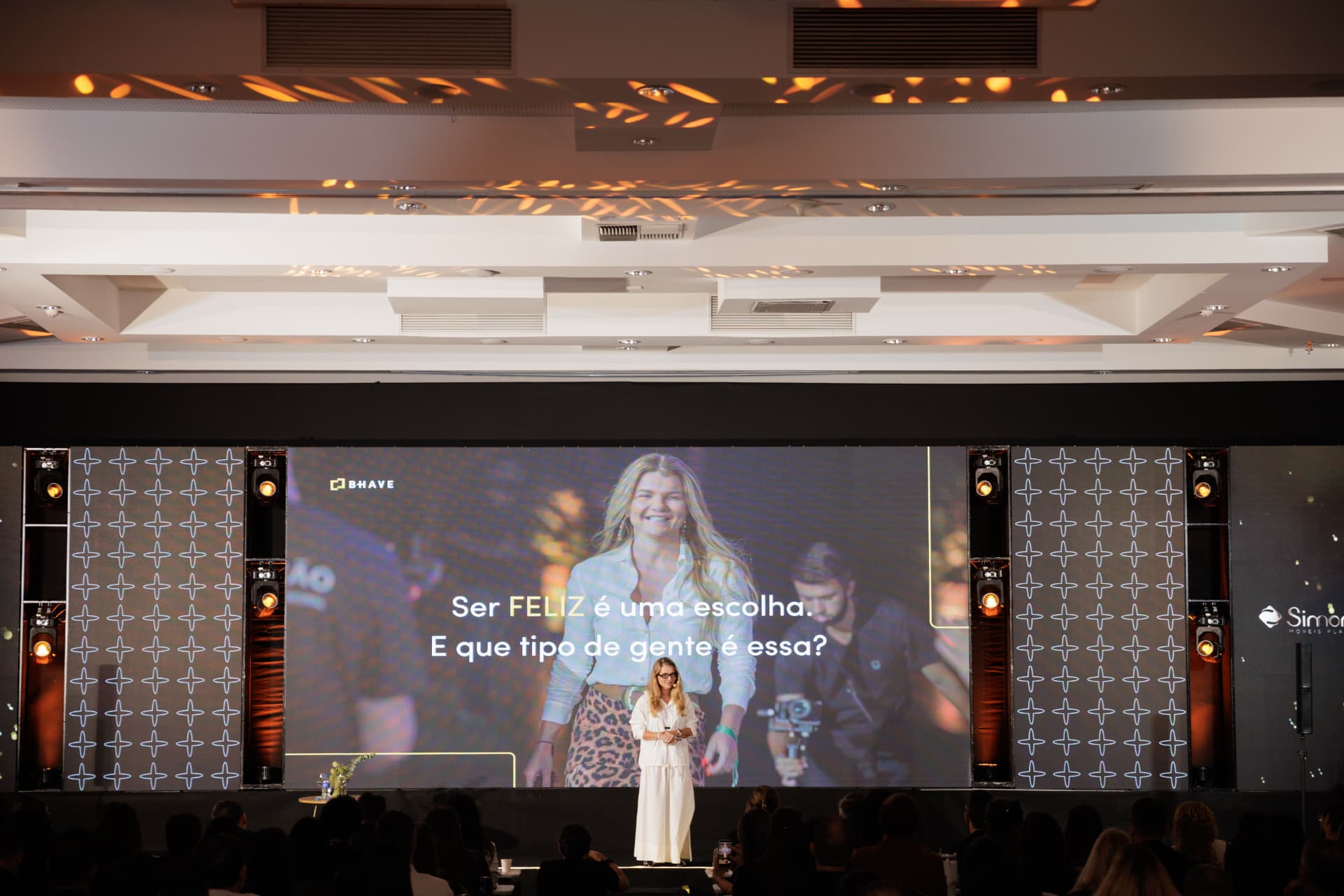 Erika Linhares em palco com telão panorâmico